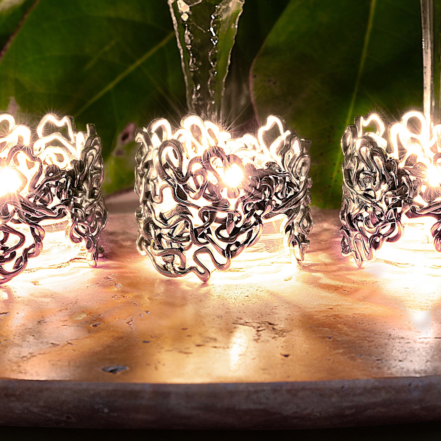 Intricate heirloom silver tealights with Mississippi River pattern cast ambient shadows in a table centerpiece.