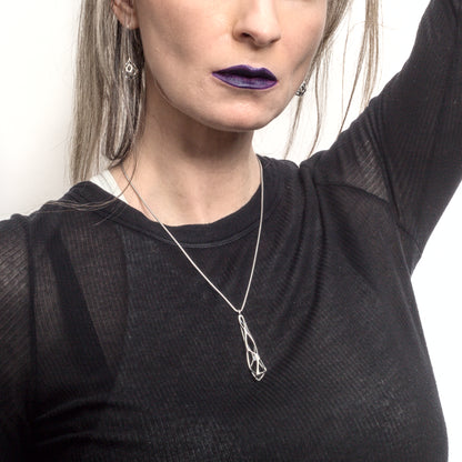 In this image. The Xover0 Tamarix necklace is styled with a black Rick Owens t-shirt and dark lipstick. It's giving "elder goth".