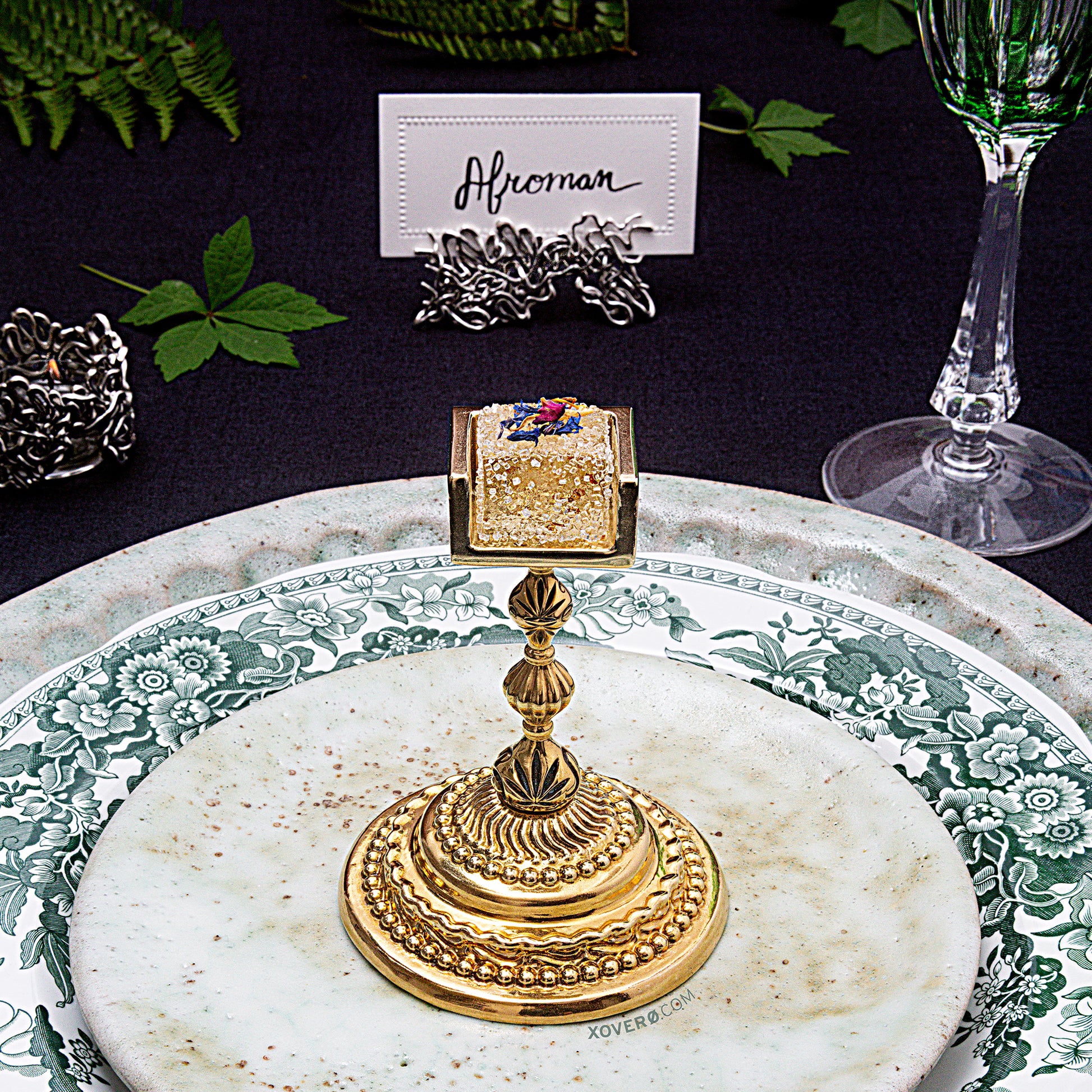 A formal dining place setting with the cannabis gummy chalice positioned in the center of the salad plate. 