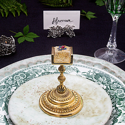 A formal dining place setting with the cannabis gummy chalice positioned in the center of the salad plate. 