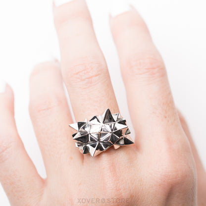 A sterling silver ring with a geometric radiating spikes design and mirror-like hand-polished finish, worn on a finger.
